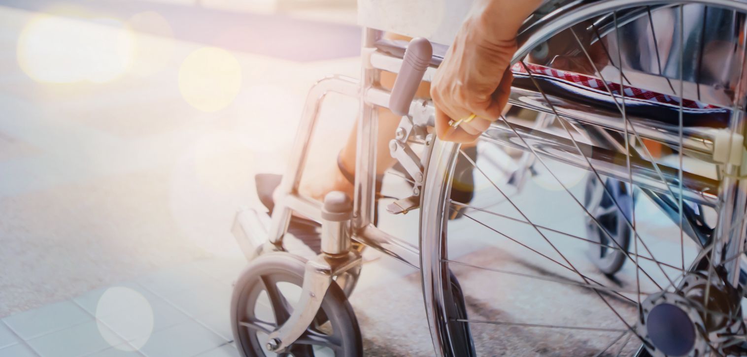 Angled shot of a person in a wheelchair close up to the hand holding the wheel