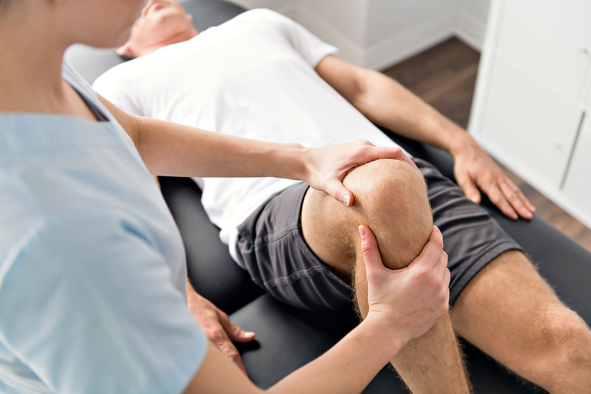 Closeup of a physical therapist working on a male's knee