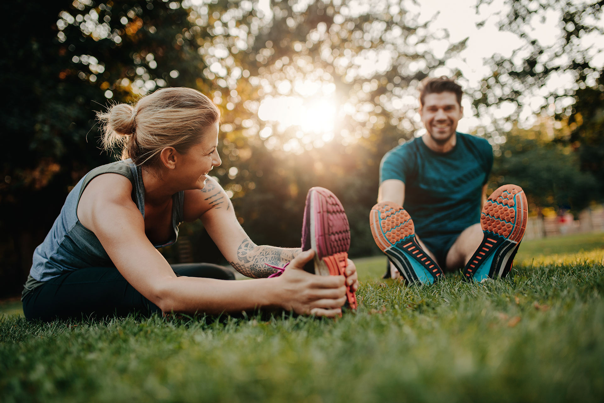 Man and woman stretching on some grass in the outdoors