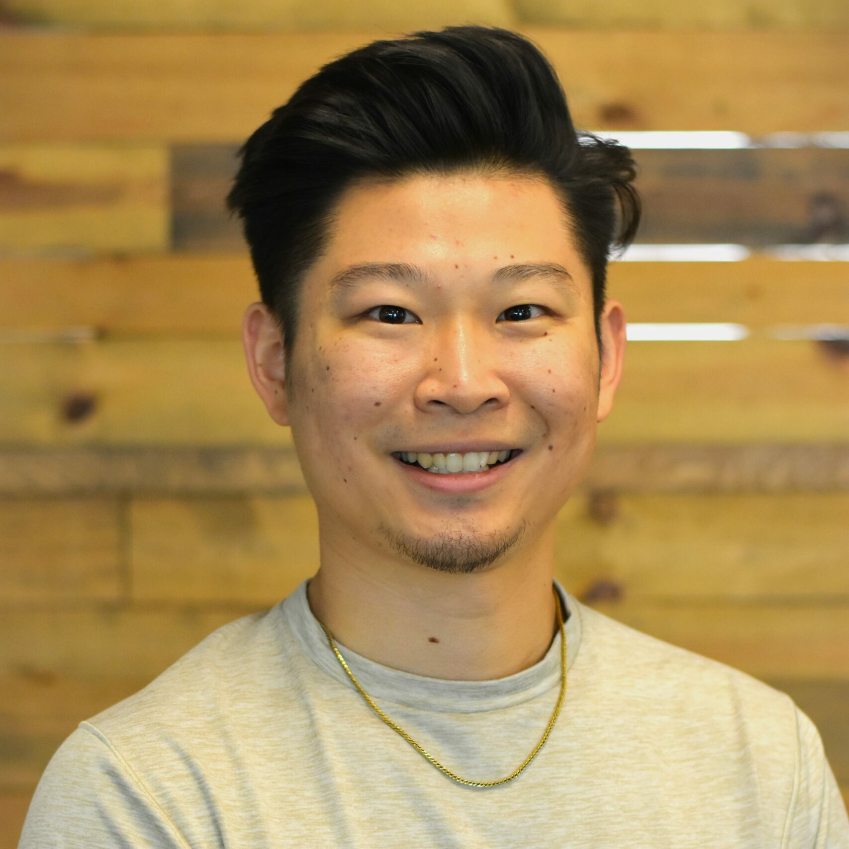 Man with facial hair and red shirt smiling